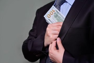 Businessman putting bribe in pocket against gray background. Con